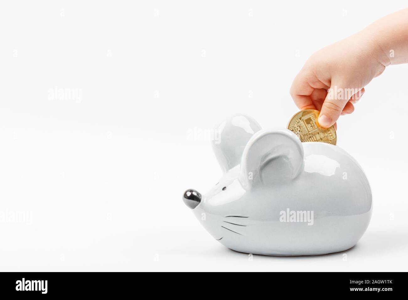 Kid's Toddler Hand ein bitcoin Münze in einer grauen Maus oder Ratte Sparschwein auf weißem Hintergrund mit Platz für Text. Konzept für Themen über Currencie Stockfoto
