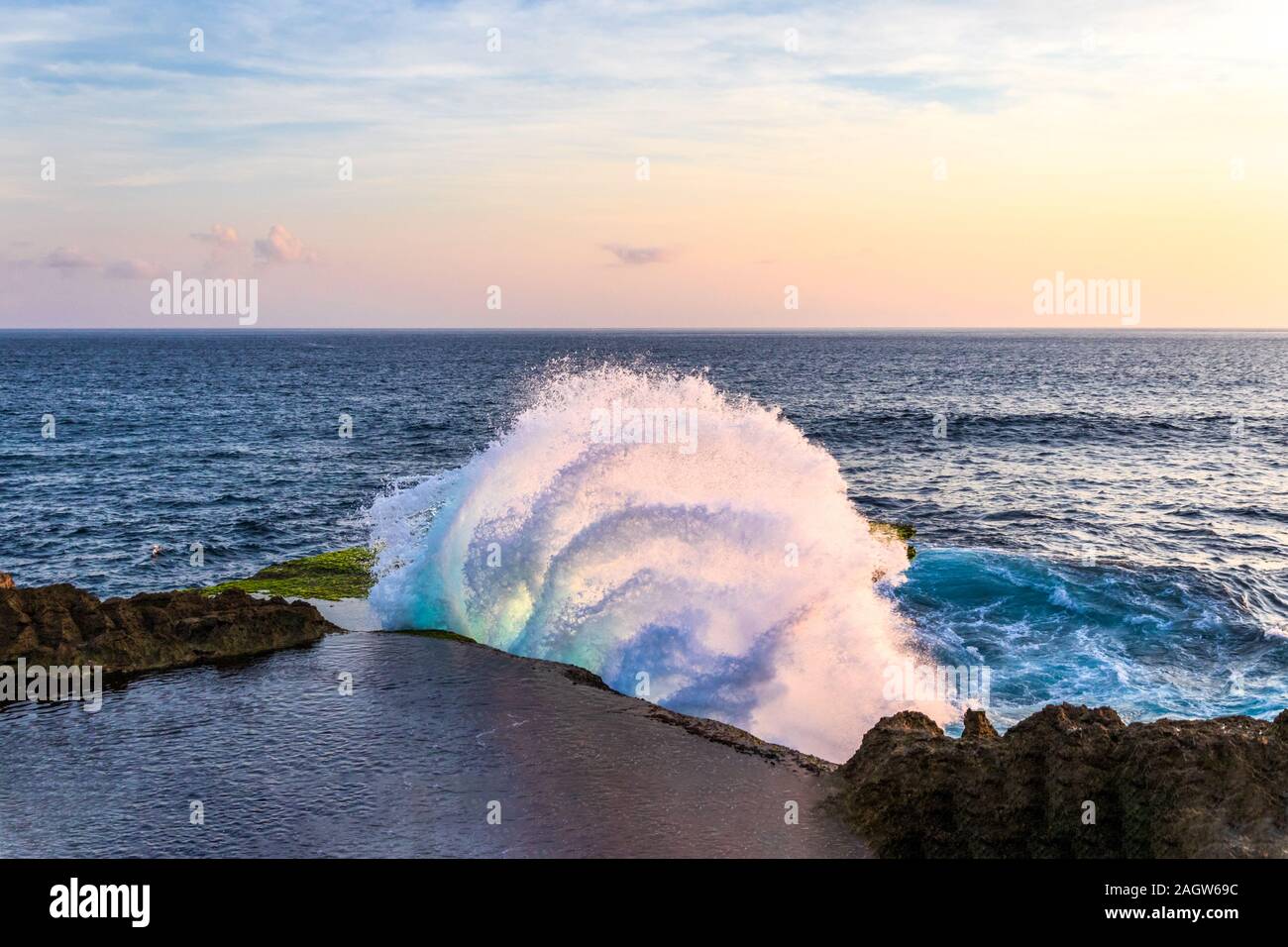 Geschwungene Welle gegen Felsen in des Teufels reißen, an der Küste von Nusa Lembongan, Bali, Indonesien. Pool von Wasser auf der Klippe im Vordergrund. Stockfoto