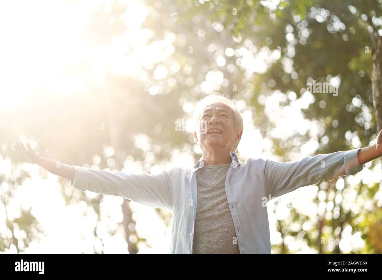 Senior asiatischer Mann genießen die frische Luft gehen mit offenen Armen draußen im Park Stockfoto