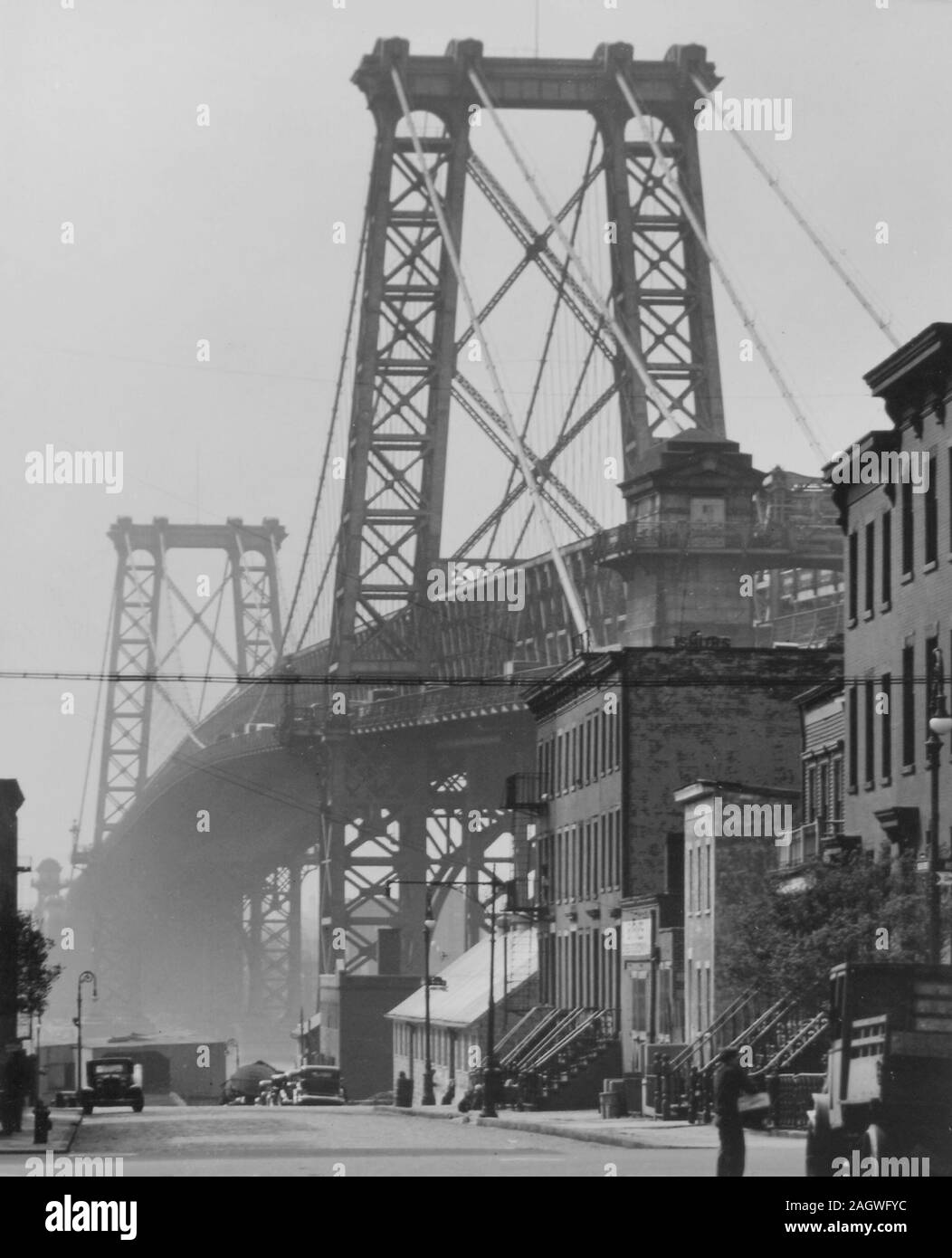 Die Williamsburg Bridge erhebt sich der Dunst über 8. Straße, die in Richtung Fluss hängen und hat Häuser und Geschäfte entlang. Stockfoto