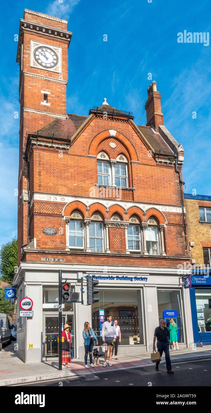 Nationwide Building Society; Zeitraum Gebäude mit Uhrturm; Überqueren von Straßen- und Frau an Geldautomaten. Heath Street, Hampstead, London, NW3. Stockfoto