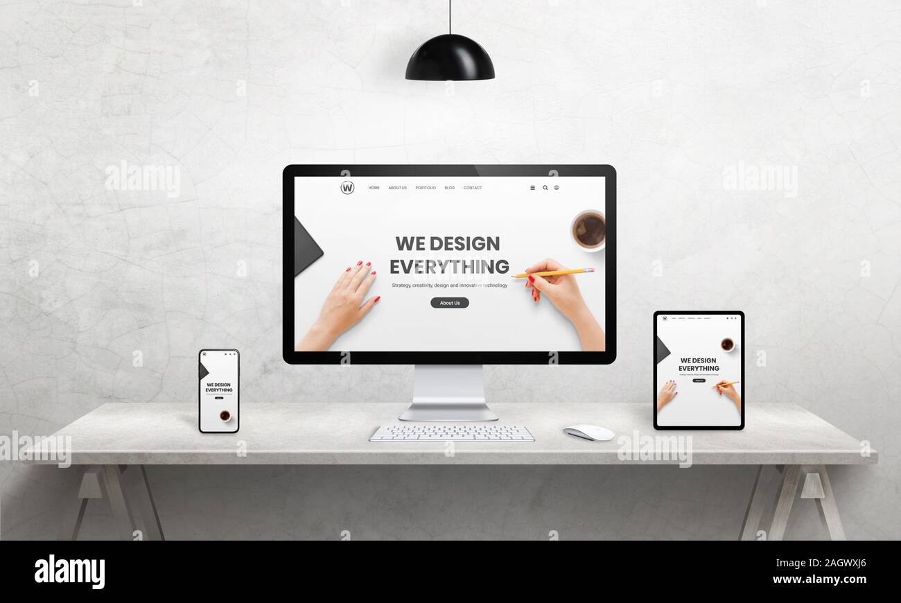 Wir gestalten alles Agentur aufmerksam Webseite auf Computer, Tablet und Telefon angezeigt. Moderne Geräte mit dünnen Kanten. Modernes Büro, Studio, Schreibtisch Stockfoto