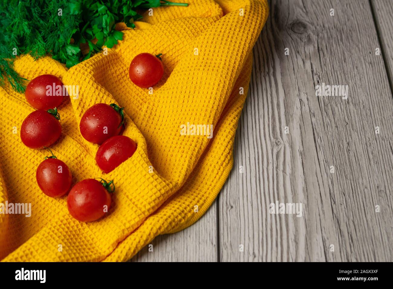 Cherry Tomaten mit Grüns auf ein gelbes Handtuch Stockfoto