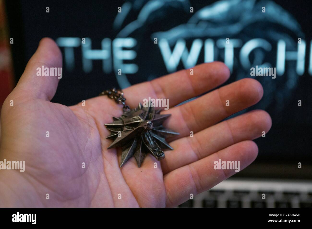 NIZHYN, UKRAINE/21. Dezember 2019: Hand mit Medaillon vom witcher Geralt, mit Logo der neuen Netflix TV-Serie Premiere "The Witcher" Stockfoto