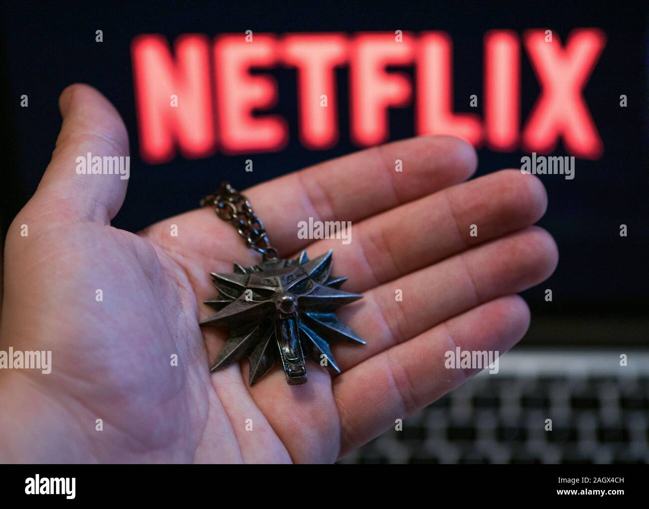 NIZHYN, UKRAINE/21. Dezember 2019: Hand der Witcher Medaillon mit Netflix Logo im Hintergrund. Neue TV-Serie "The Witcher" Premiere Stockfoto