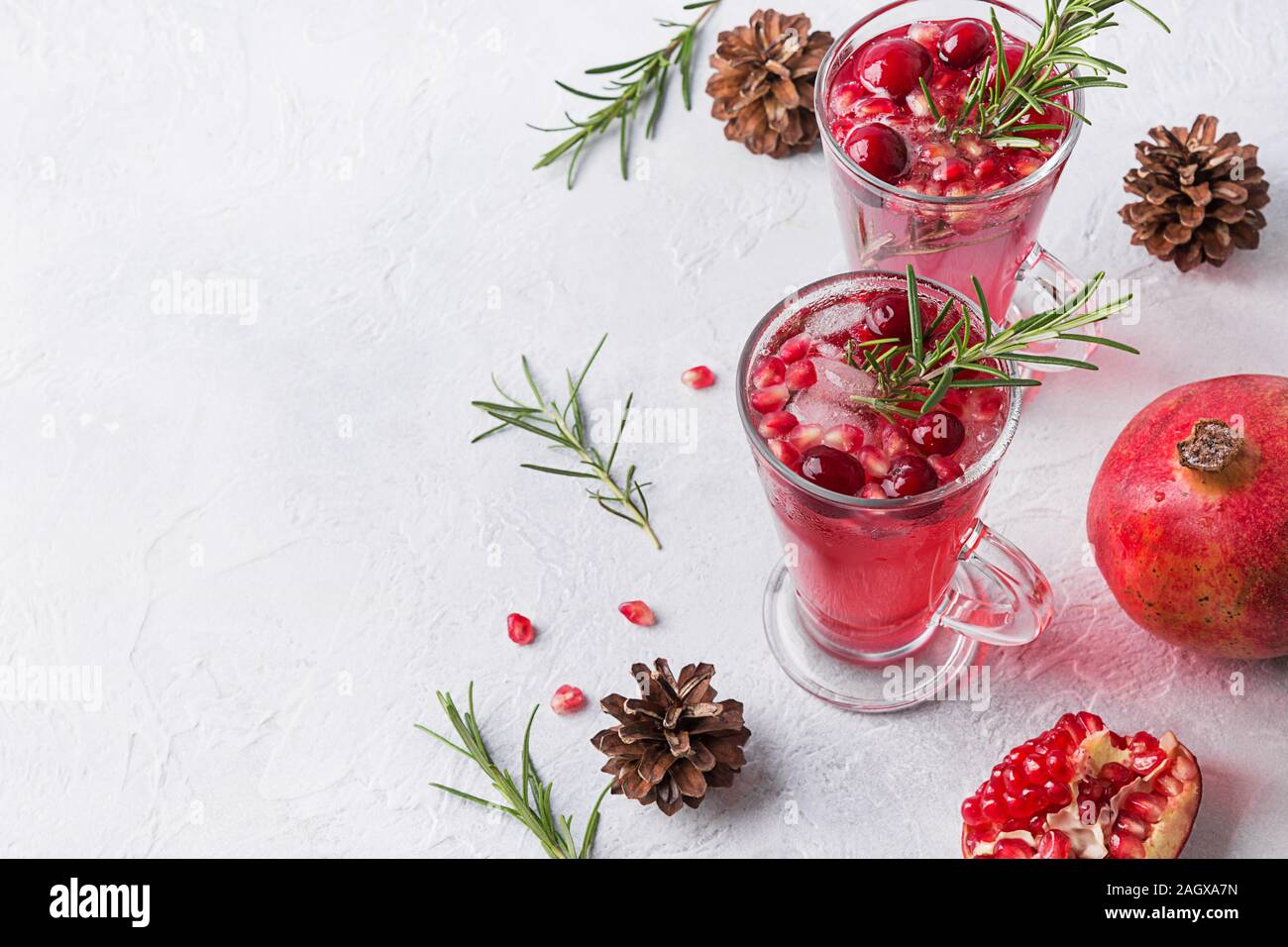 Zwei Glas Granatapfel Weihnachten Cocktail mit Rosmarin, Moosbeere, Sekt auf weißer Tisch. Xmas trinken. Platz für Text. Stockfoto