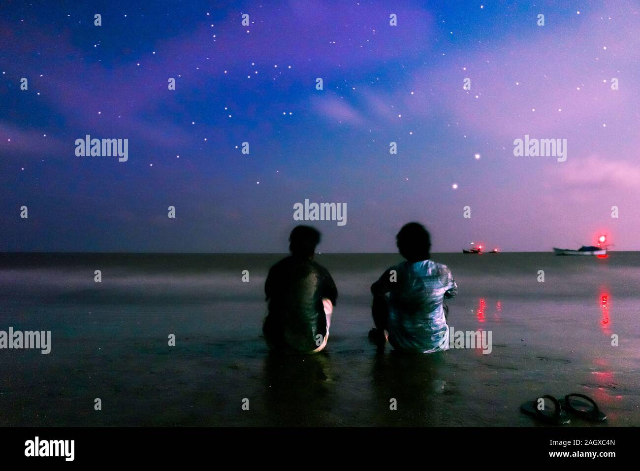 Zwei Freunde sitzen am Kuakata Strand in der Nacht. Stockfoto
