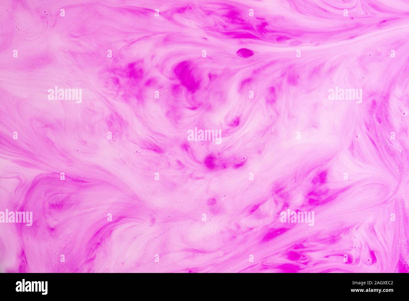 Ein Makro Foto von Tropfen pink Lebensmittelfarbe wirbelte und gemischt in dicken, cremigen weiße Milch Eine marmorierte Milchshake Effekt zu geben Stockfoto