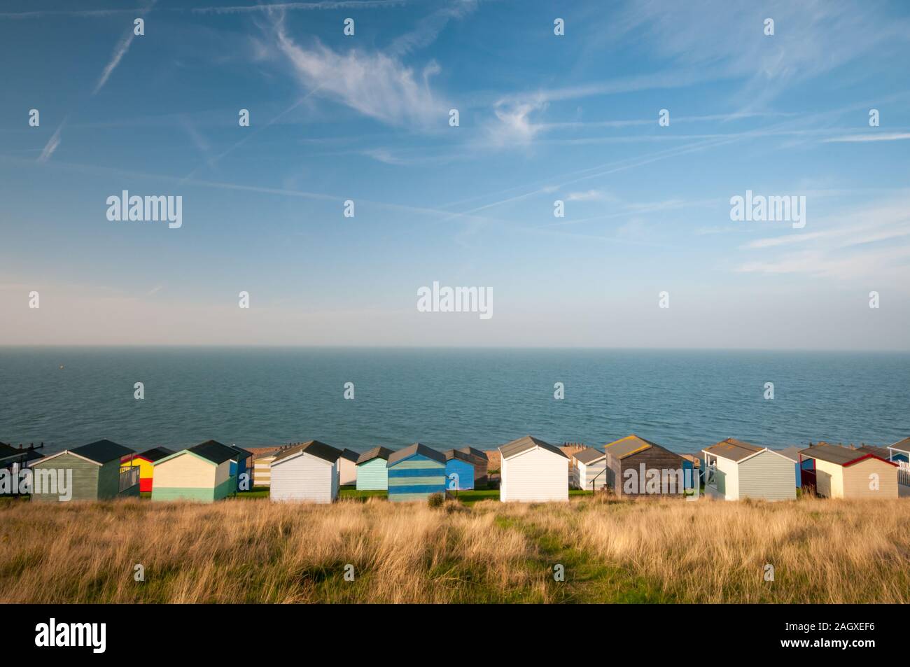 Bunte Urlaub hölzernen Umkleidekabinen am Strand mit Blick auf die ruhigen Atlantik gegen einen blauen bewölkten Himmel. Bei Kent Großbritannien Whitstable Stockfoto