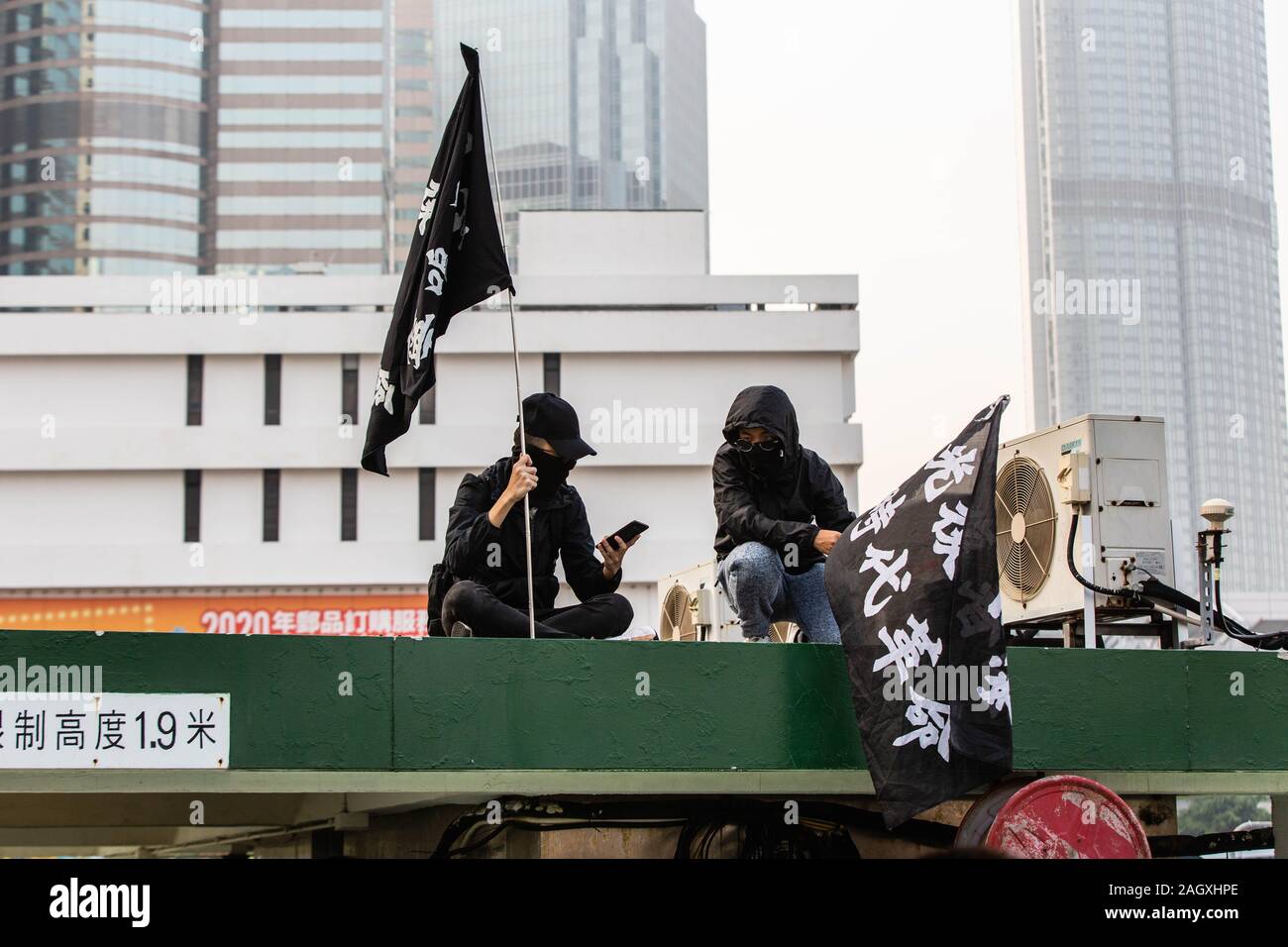 Maskierte Demonstranten Flaggen während der Demonstration Halten. 6. Monat der Unruhen, die demonstranten an einer Kundgebung in Solidarität mit den Uiguren in Xinjiang. Reden wurden der Organisatoren der Veranstaltung gegeben. Polizisten erschienen und wurden von maskierten Demonstranten konfrontiert. Stockfoto