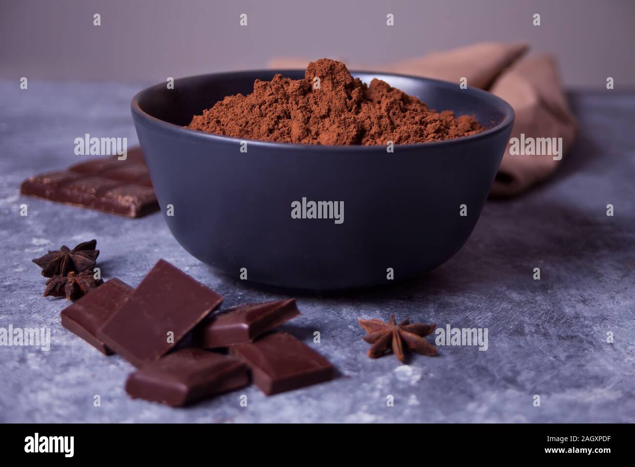 Schüssel mit Kakaopulver und Stücke Schokolade auf dem grauen Hintergrund. Stockfoto