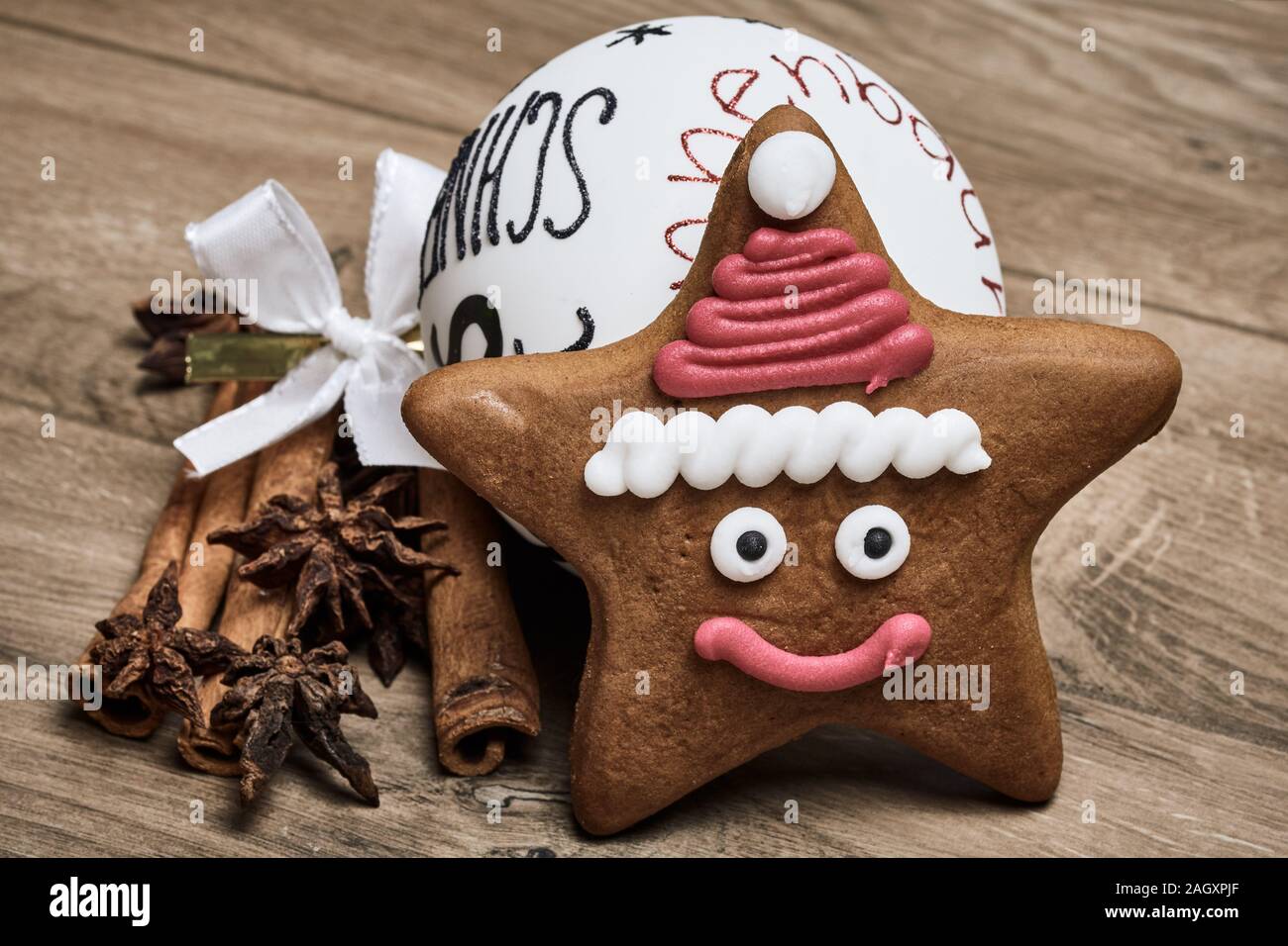 Weihnachtsmann Lebkuchen Stern, Zimtstangen, Sternanis und ein Weihnachtsbaum Kugel auf Holz- Hintergrund Stockfoto