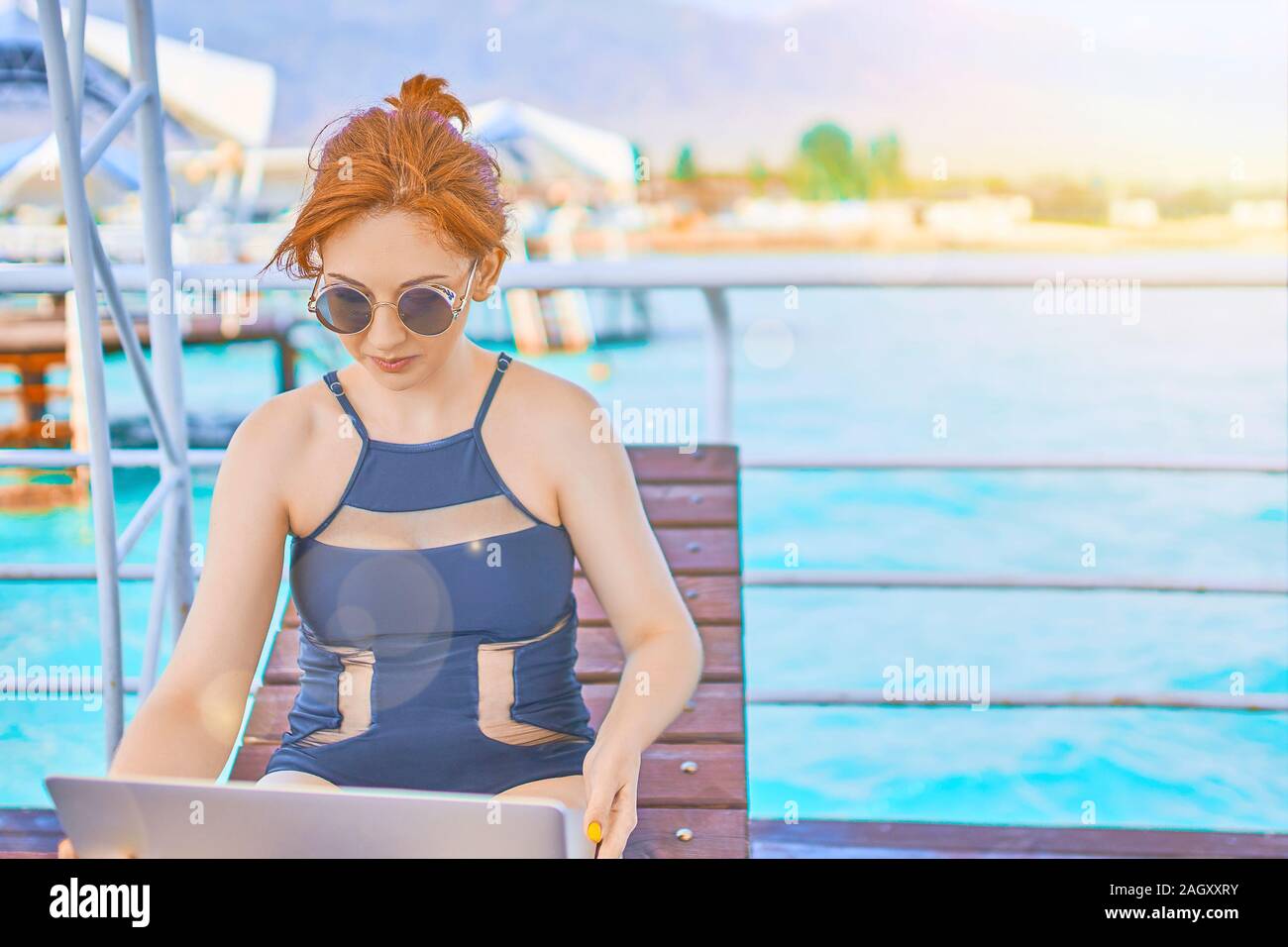 Rothaarige Mädchen arbeiten mit einem Laptop auf dem Meer. Weibliche Freiberufler arbeiten am Strand. Attraktive Haar Frau mit Laptop am Strand und Blick auf die Stockfoto