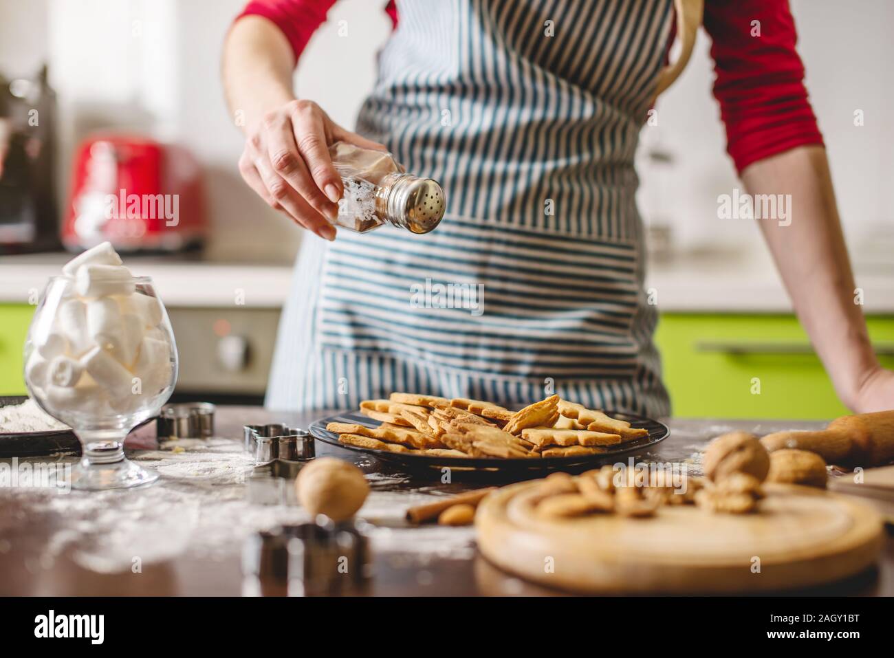 Cook Hausfrau cookies zu Hause auf eine bunte Küche. Eine Frau mit einer Platte mit bereit Golden frisch gebackene Kekse in der Form von Weihnachten Stockfoto