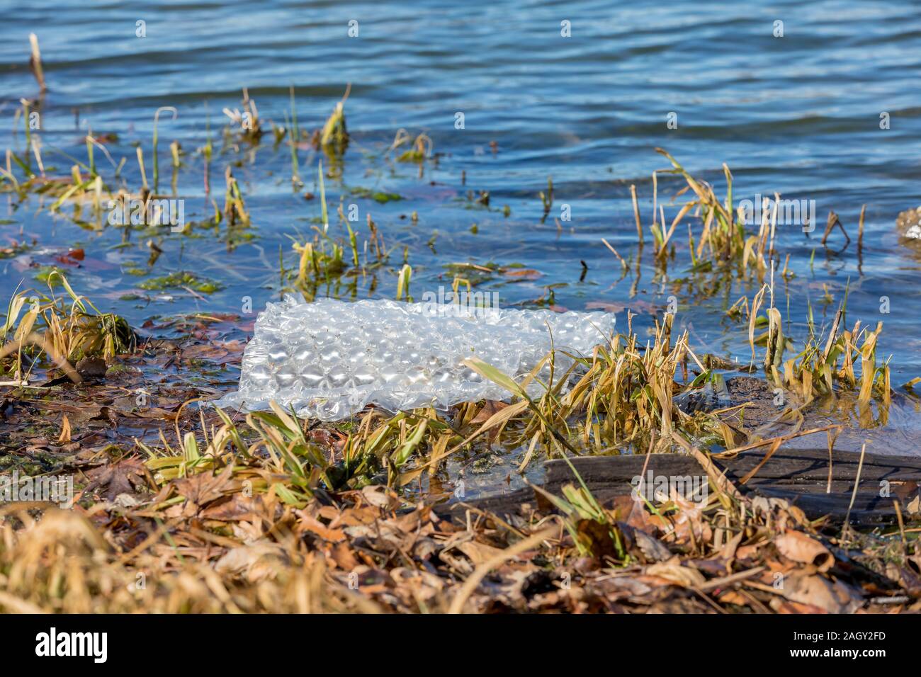 Kunststoff Bubble Wrap floating im blauen Wasser des Sees. Konzept der Wasserverschmutzung, Abfall und Recycling Stockfoto