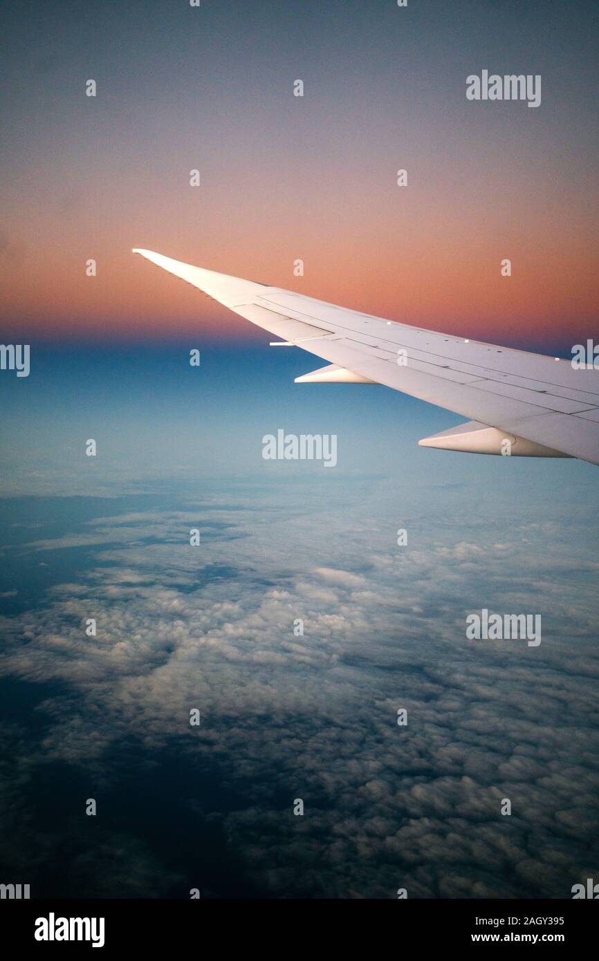 Flügel eines Flugzeugs aus dem Fenster während des Fluges gesehen bei Sonnenaufgang Stockfoto