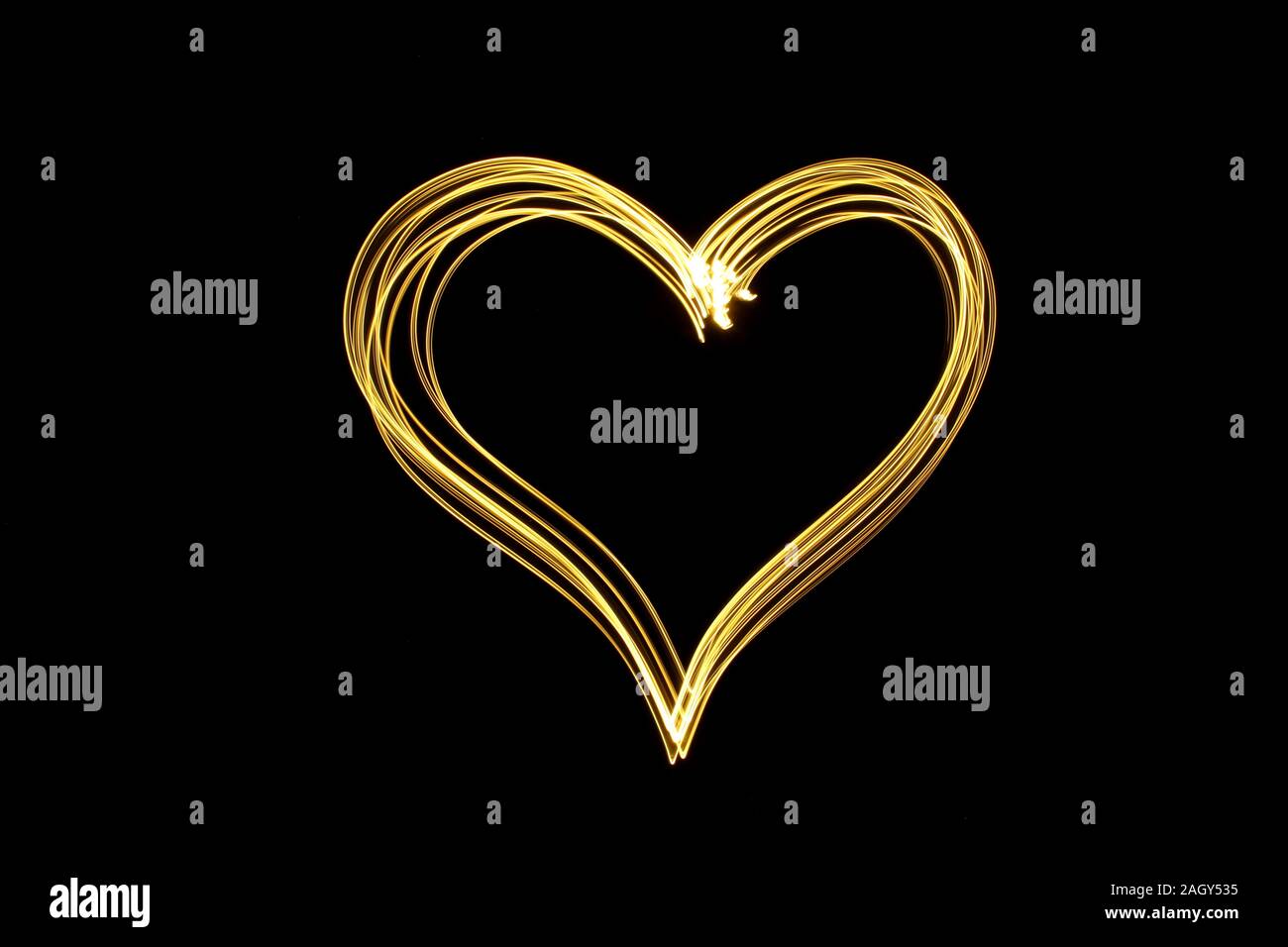 Licht Malerei Fotografie einer Herzform Umrisse, vibrant Neon Farbe gold auf schwarzem Hintergrund. Fotos mit langer Belichtungszeit. Liebe, Romantik. Stockfoto