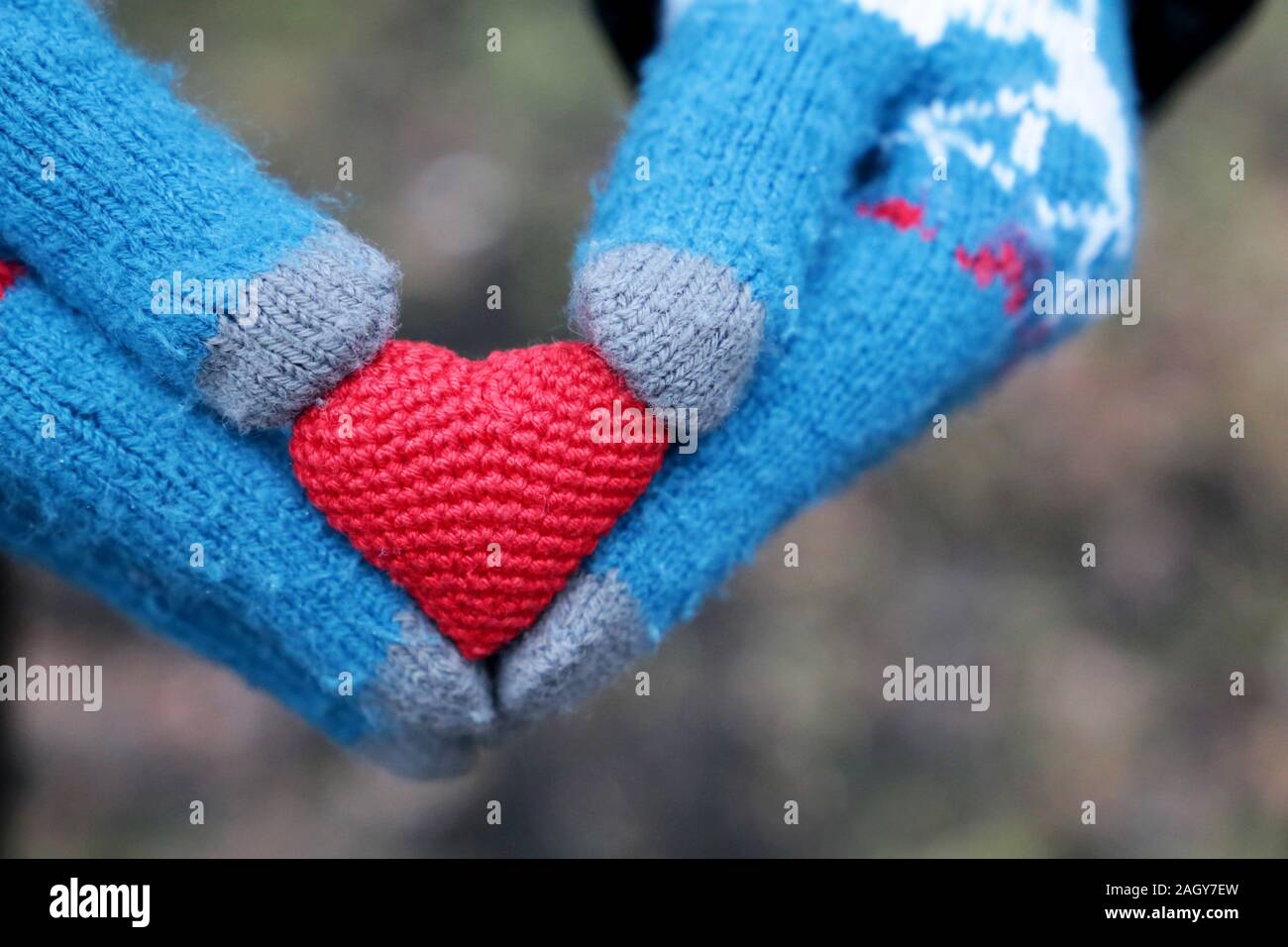 Rot gestrickt Herz in weibliche Hände in Handschuhe aus Gewirken, romantische Liebe. Konzept der Weihnachten, Valentinstag, Winter Wetter Stockfoto