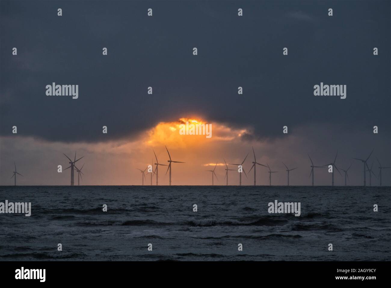 Walney Island, Cumbria, Großbritannien. 22. Dezember 2019. UK Wetter. Nach einem kalten, feuchten und regnerischen Tag aus der Grafschaft Cumbria Küste die Sonne durch die Wolken bricht. Blick über die Irische See von Walney Island in Richtung Walney Offshore-windfarm, die größte der Welt. Credit: greenburn/Alamy Leben Nachrichten. Stockfoto