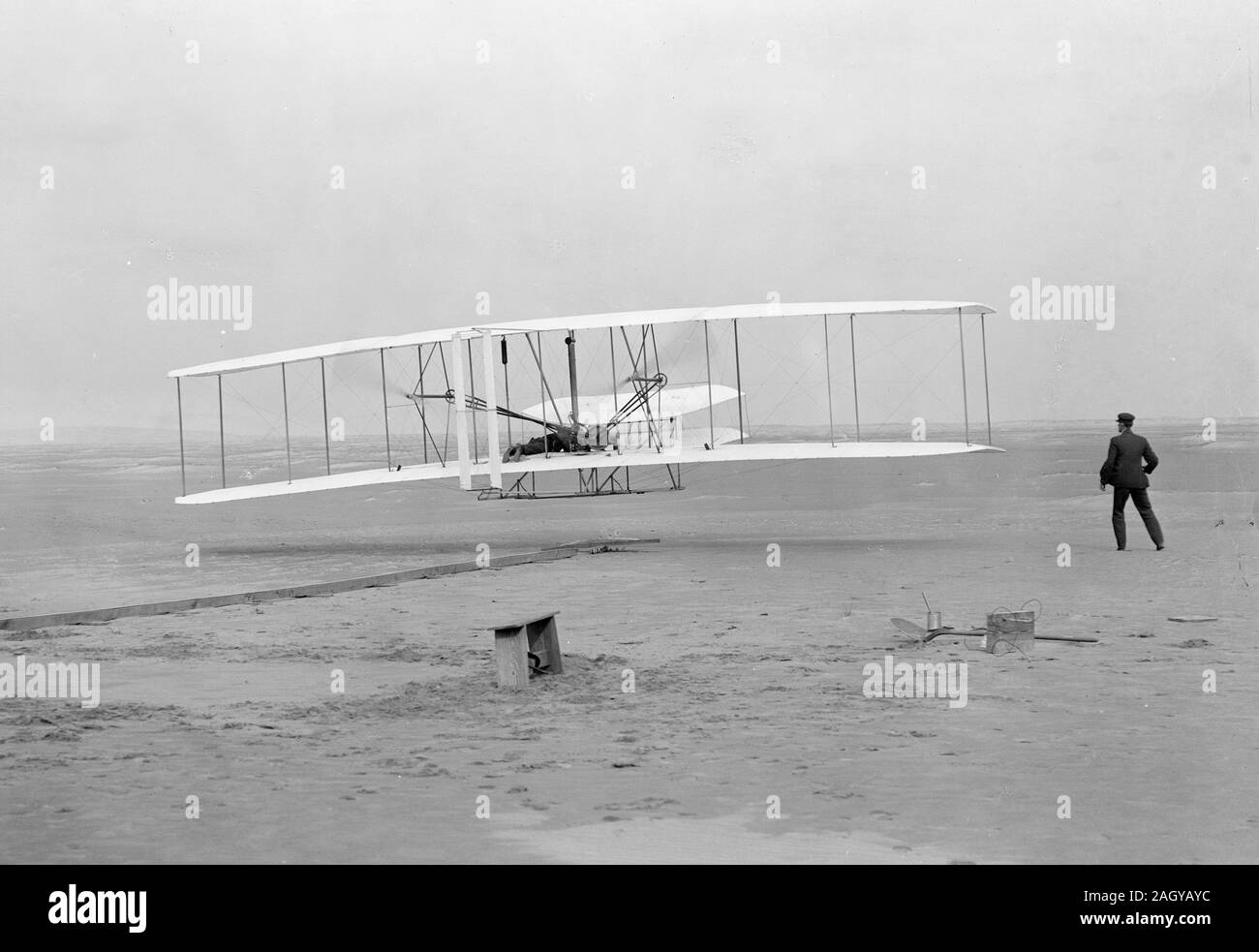 Die Brüder Wright, der zum ersten Mal eingeschaltet, kontrollierten, nachhaltigen Flug. Orville Wright auf die Bedienelemente der Maschine, liegend anfällig auf der unteren Tragfläche mit den Hüften in der Wiege, die den Flügel - warping Mechanismus betrieben. Wilbur Wright, die neben der Maschine Balance, erster Flug, 120 Meter in 12 Sekunden, 10:35 Uhr; in Kitty Hawk, North Carolina First Flight, 17. Dezember 1903. Stockfoto