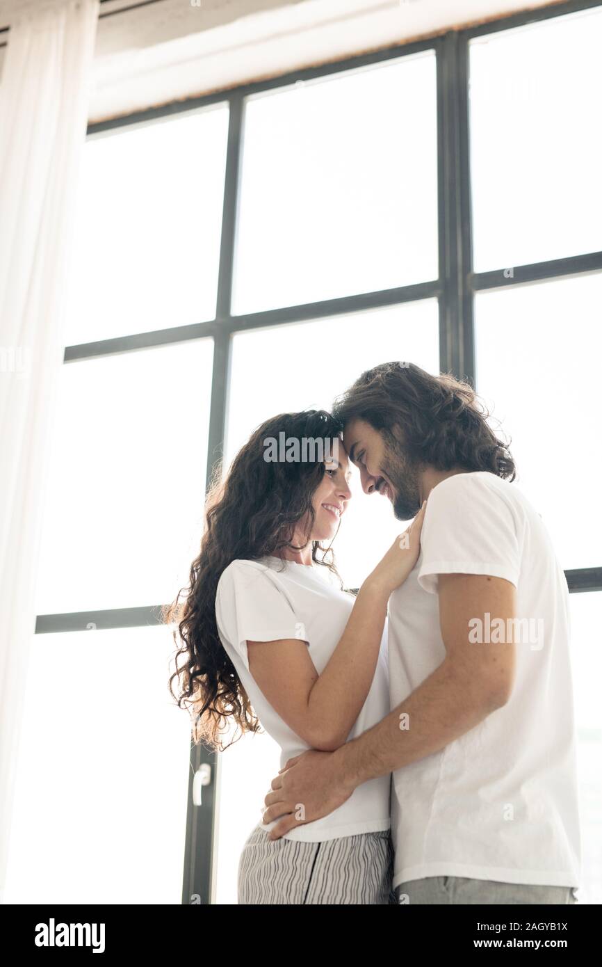 Junge zärtlich lächelnd Paar in den weißen T-Shirts in der Nähe jedes anderen Stockfoto