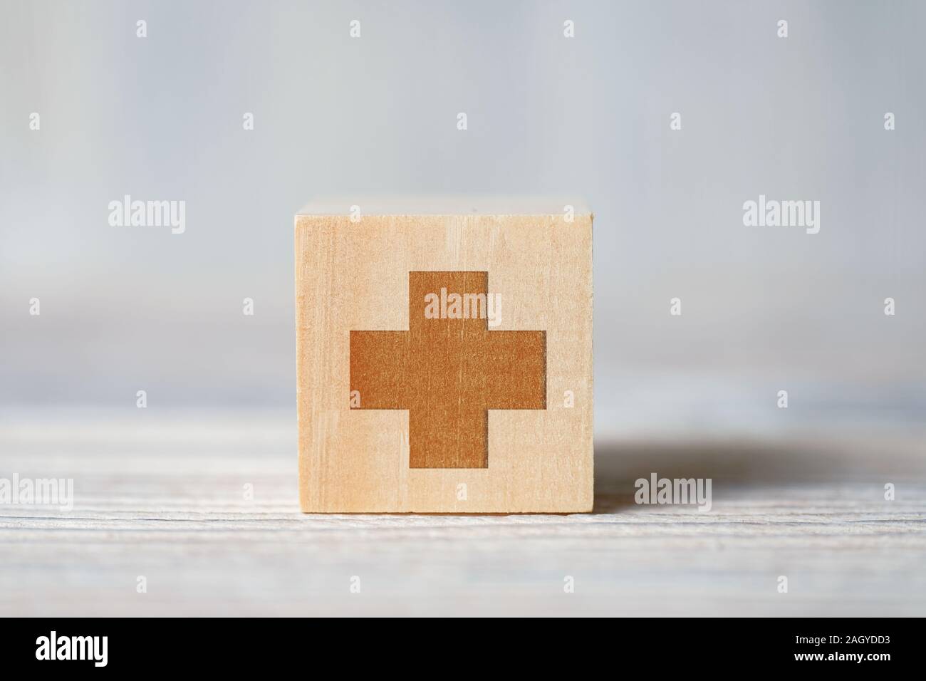 In der Nähe der Medizinischen Symbol des Kreuzes auf Würfel auf Holz- Hintergrund. Konzept der medizinische Unterstützung, Gesundheit, Lebensversicherung, vhi. Stockfoto