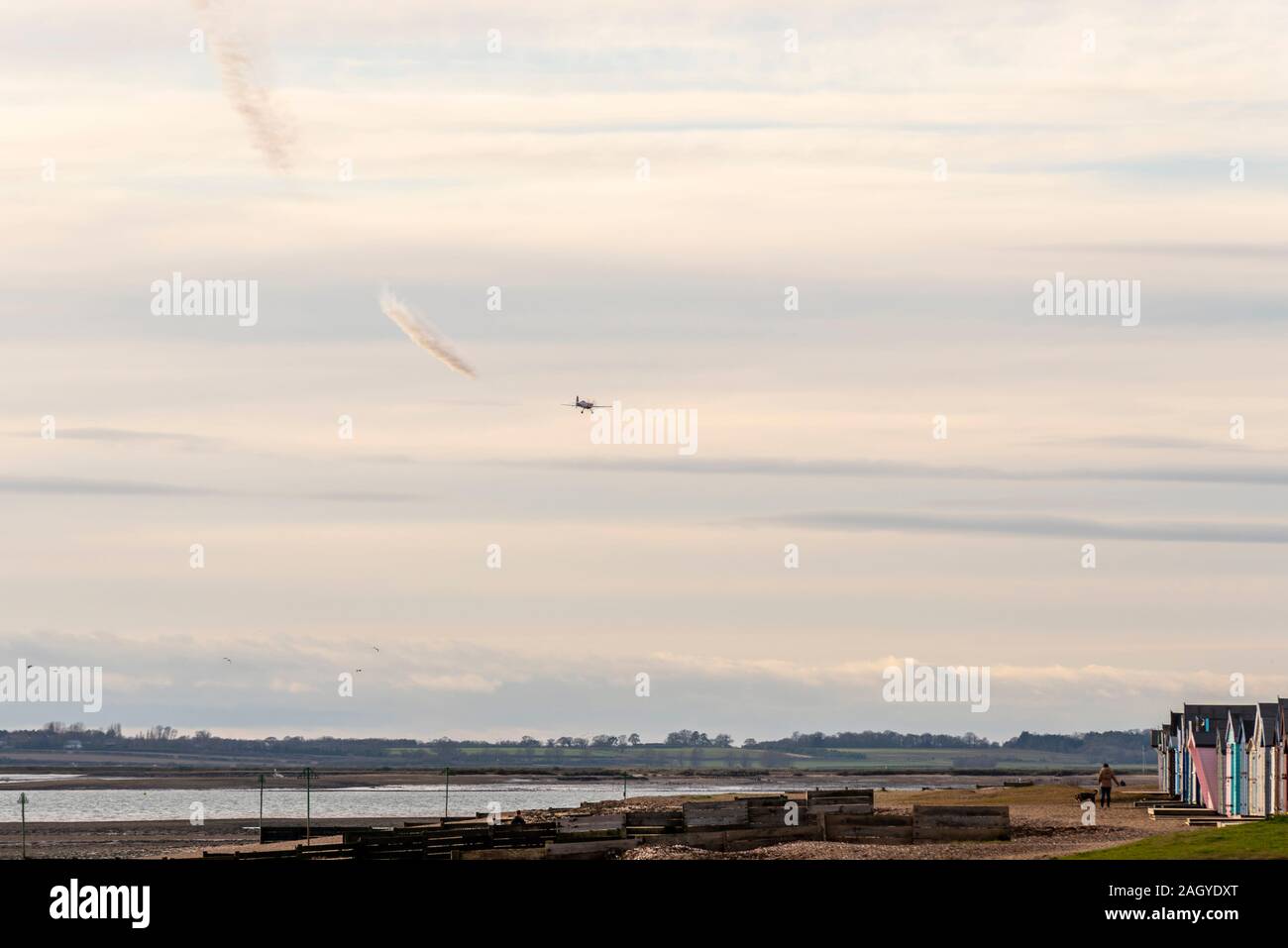 Aerobatic Flugzeug über dem Fluss Blackwater an der West Mersea, mersea Island, Essex, UK fliegen. Durch Person und Hund bewacht. Private Anzeigen. Rauchfahne Stockfoto