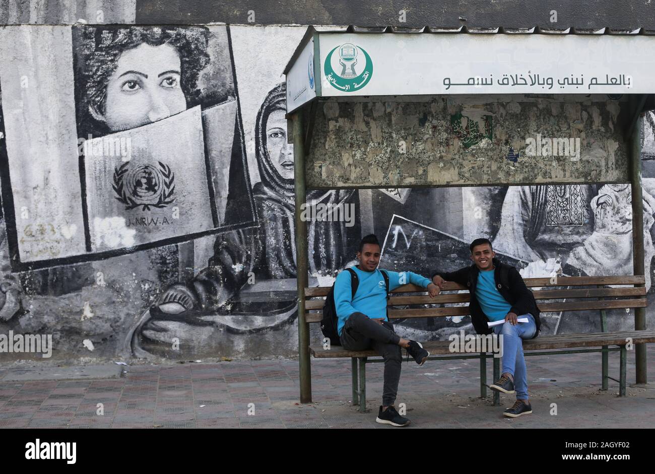 Gaza, Palästina. 22 Dez, 2019. Palästinensische jugendliche Sitz neben einem Wandbild an der Wand der Vereinten Nationen für Flüchtlinge (UNRWA) in Gaza Stadt. Credit: Mahmoud Issa/SOPA Images/ZUMA Draht/Alamy leben Nachrichten Stockfoto