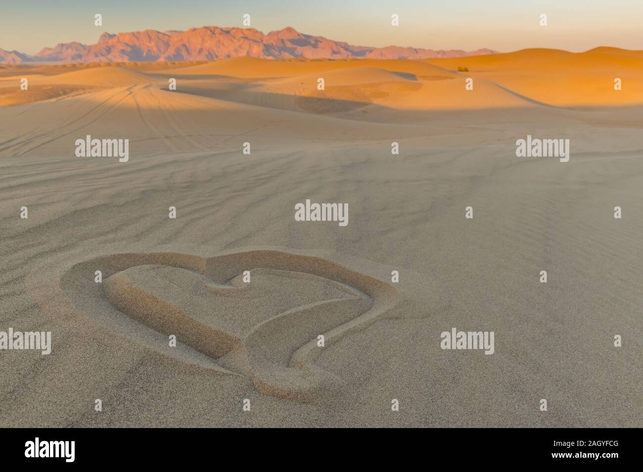 Sonnenuntergang in der Wüste, ein Herz in den Sand gezeichnet. Stockfoto