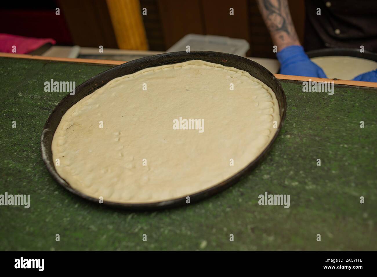 Pizza Teig in die Pfanne geben. Pizza leer. Der Koch bereitete die Grundlage für die Pizza Teig Stockfoto