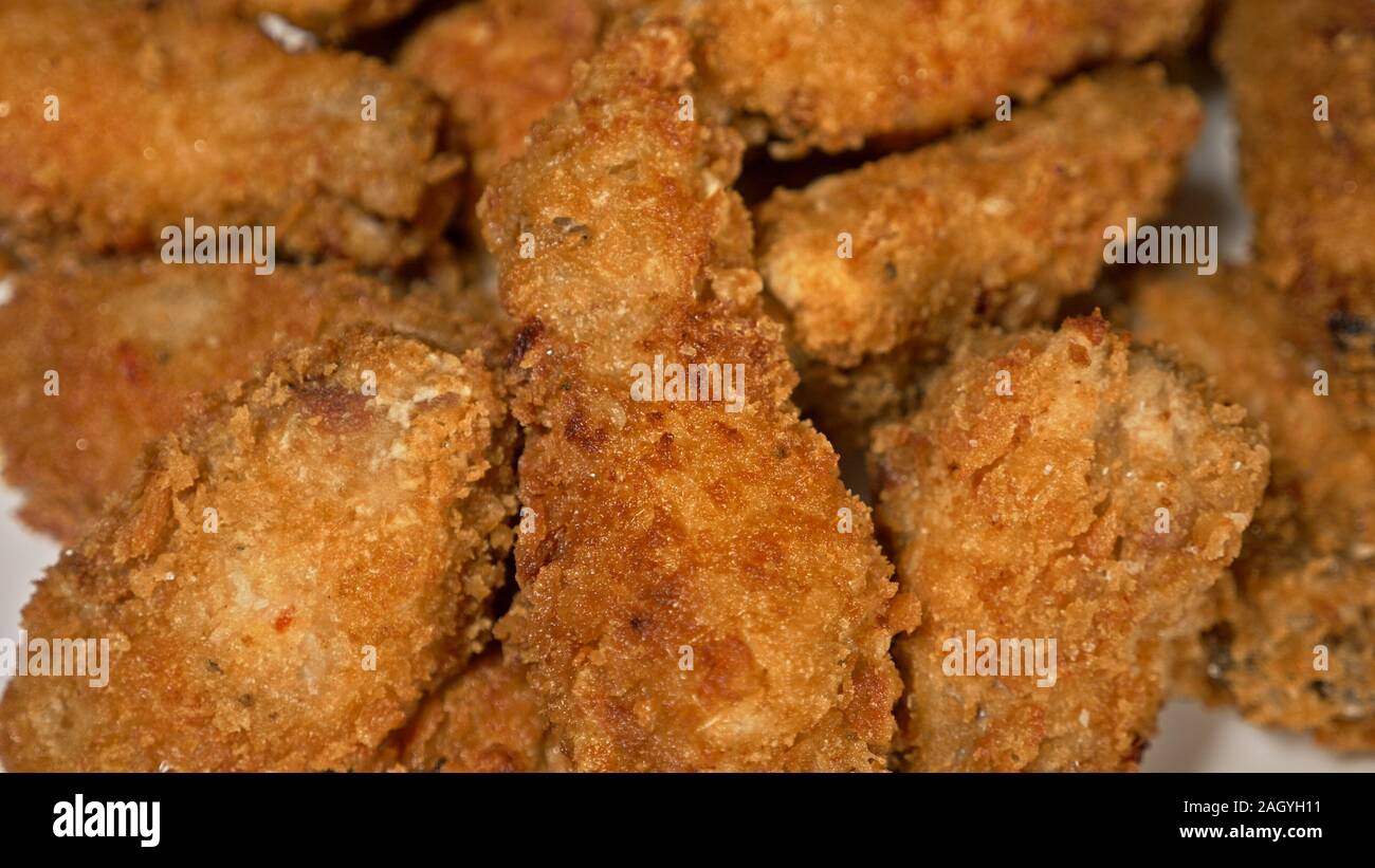 Cool schöne Frische saftige gekocht Chicken Wings in Panade. Buffalo Wings Spread auf Essen in weiße Platte. Kochen mit Friteuse Fry Maschine. Stockfoto