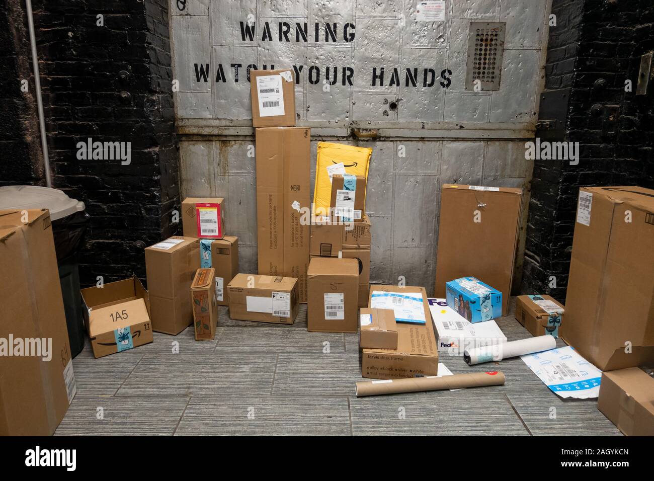 Amazon USPS, FedEx und andere on-line-Einkaufen Delivery Packages gestapelt aus einem Appartement e-mail Zimmer in Brooklyn, New York, USA, gesammelt zu werden Stockfoto