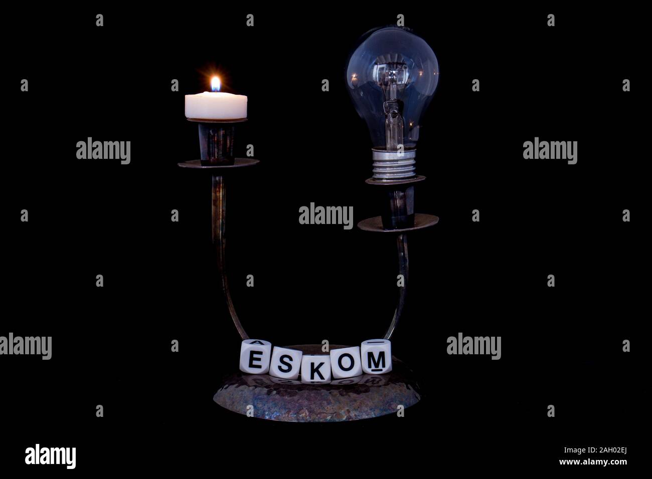 Ein Kerzenhalter mit einer abgesicherten elektrischen Glühbirne eine Kerze und den Namen Eskom auf schwarzem Hintergrund Bild im Querformat isoliert Stockfoto