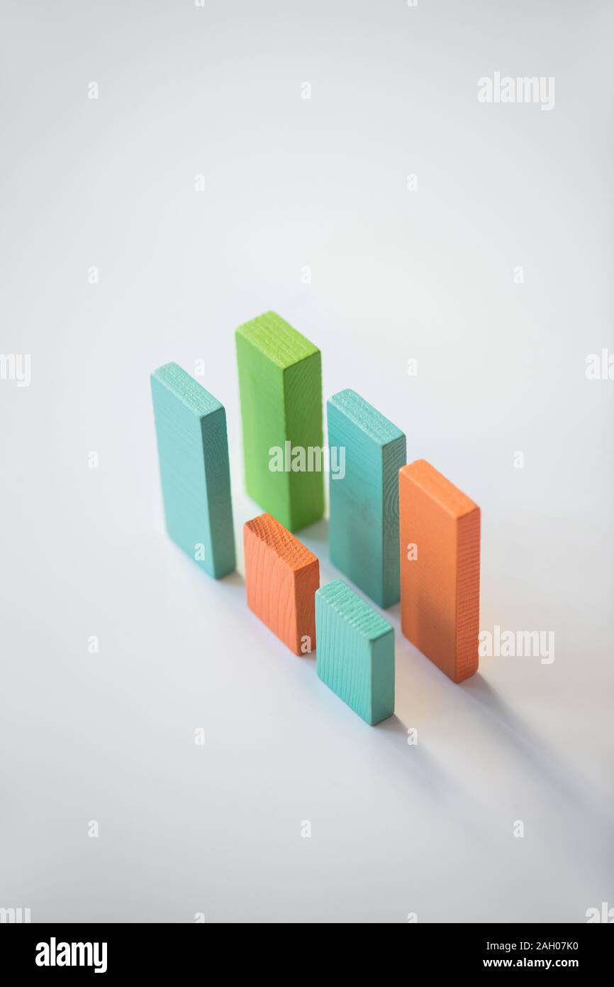 Zwei parallelen Blau, Orange und Grün Holz Steine bilden Finanzcharts in Isolation auf weißem Hintergrund Stockfoto
