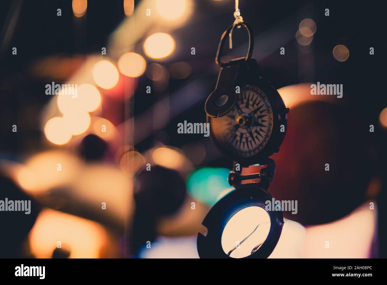 Schönes Bokeh eines Kompass hängen mit Lichtern und Überlegungen in den Hintergrund. Konzept verloren zu gehen, Freiheit und Streben nach Glück. Stockfoto