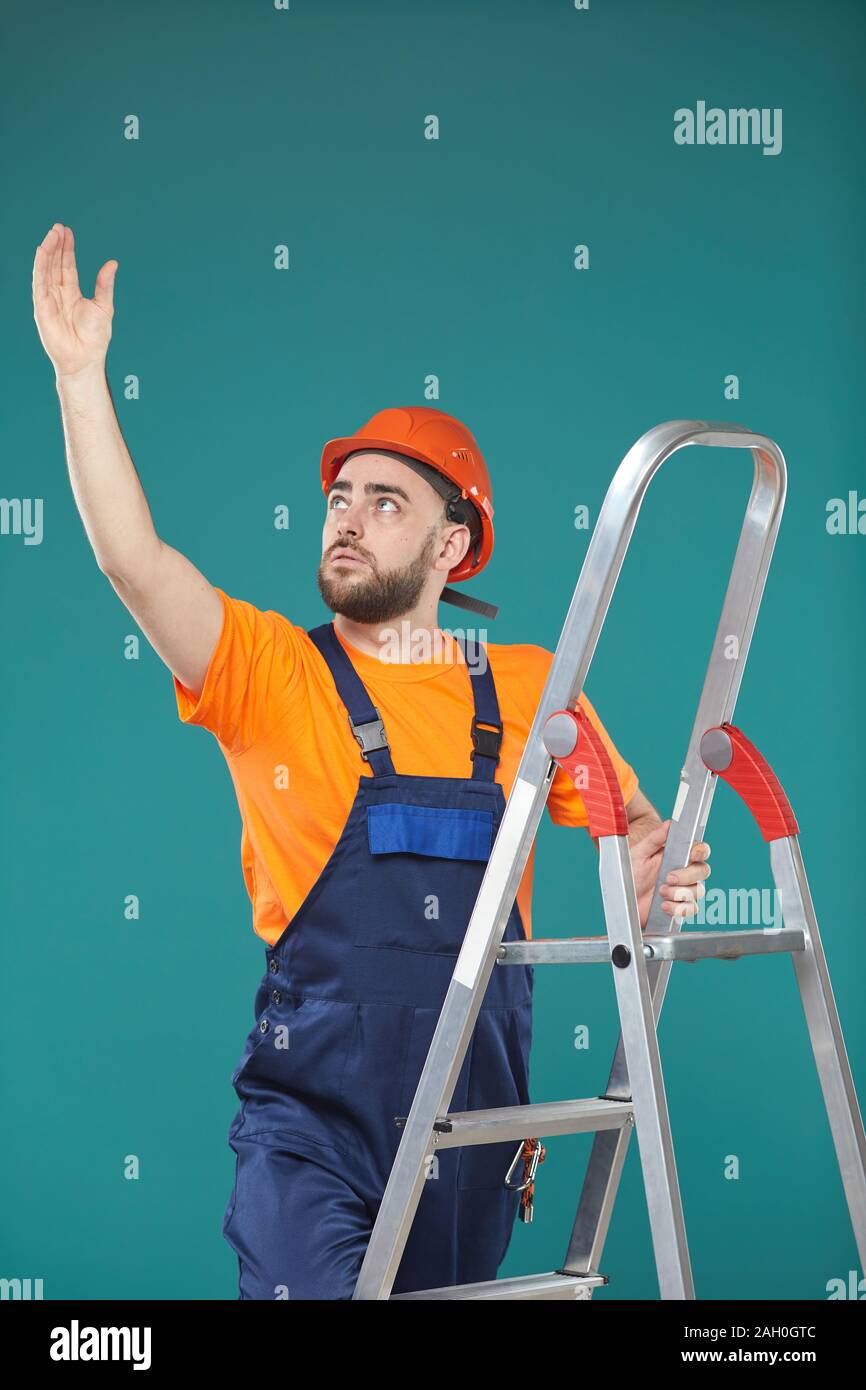 Kaukasische männliche Arbeiter stehen auf tragbare Leiter versuchen, etwas zu erreichen, Studio Portrait Stockfoto