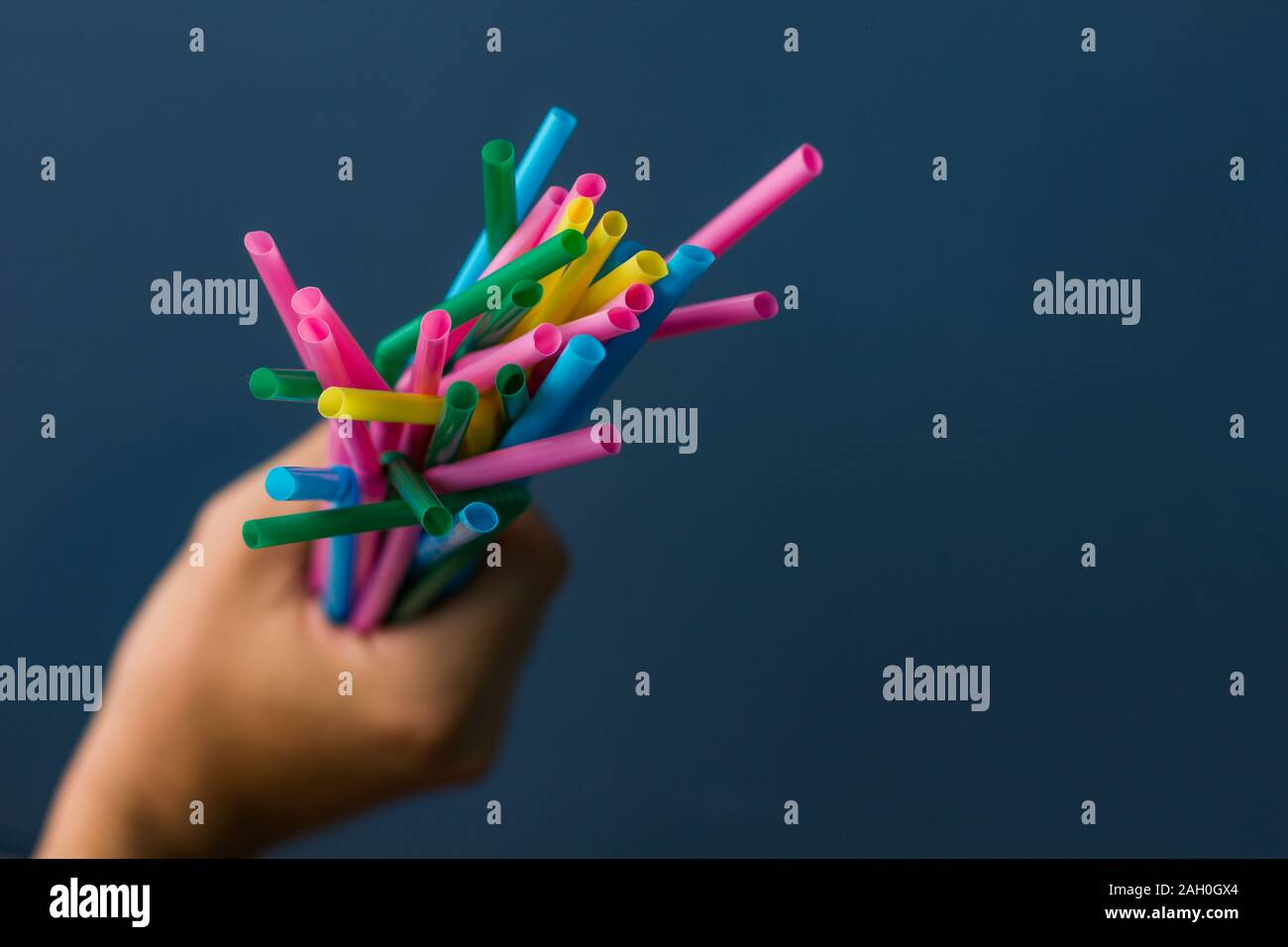 Nahaufnahme einer Hand, die Bambus Strohhalme auf blauem Hintergrund Stockfoto