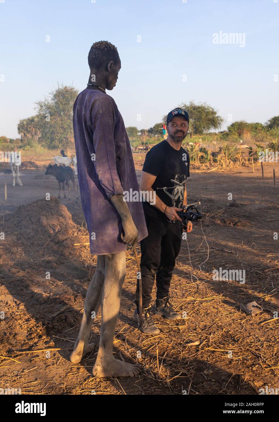 Westliche Touristen mit einem hohen mundari Mann, Central Equatoria, Terekeka, South Sudan Stockfoto