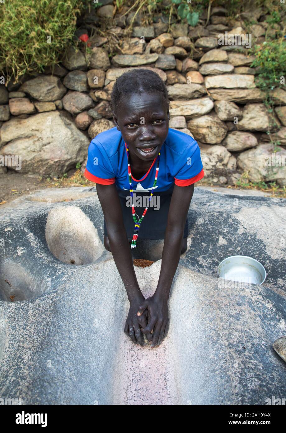 Lotuko Stamm Frau Schleifen Körner in ein Loch im Felsen, Central Equatoria, Illeu, South Sudan Stockfoto