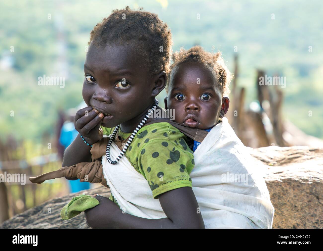 Lotuko Stamm Mädchen ihre Schwester, die ihr zurück, Central Equatoria, Illeu, South Sudan Stockfoto
