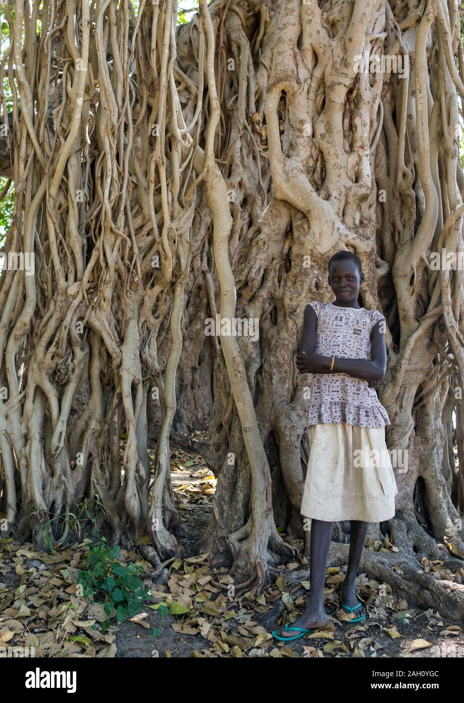 Stehendes Mädchen vor einem riesigen Baum, Central Equatoria, Terekeka, South Sudan Stockfoto
