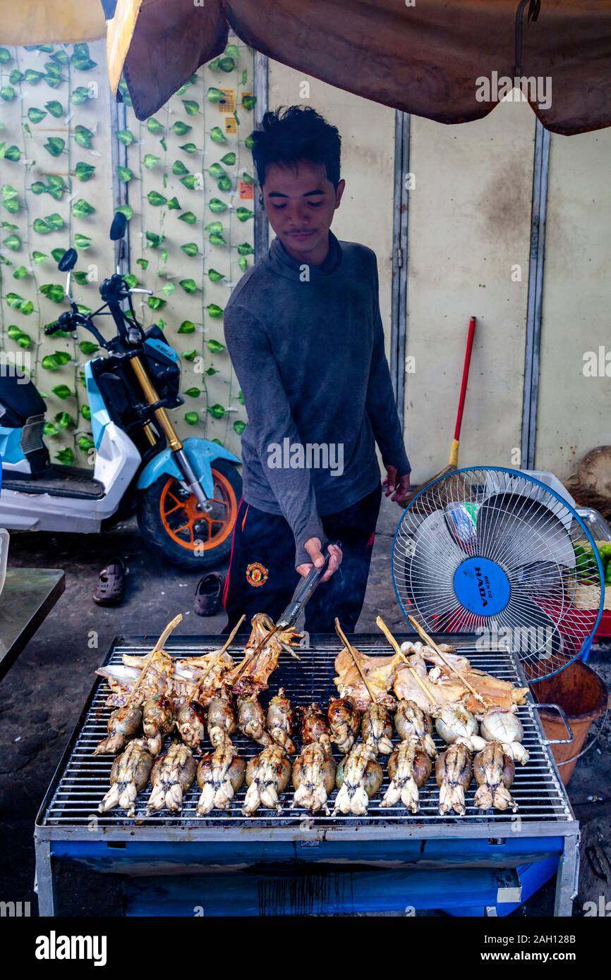 Ein junger Mann Kochen Fleisch auf dem Grill, Phnom Penh, Kambodscha. Stockfoto
