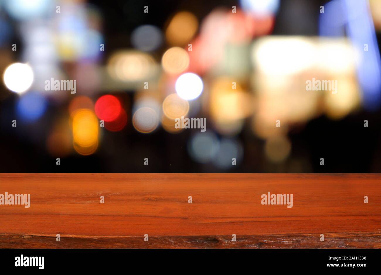 Leeren dunklen Holztisch vor abstrakten verschwommenen Hintergrund des Cafe coffee shop Stadt Nacht Licht. können für die Anzeige verwendet werden oder Montage ihrer Produkte Stockfoto