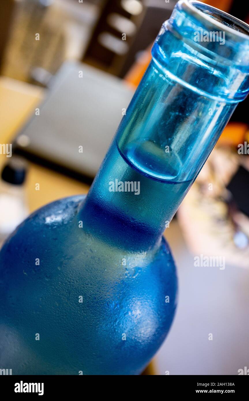 Detailansicht der Hals einer blauen Flasche Wasser auf einem Tisch in einer Bar nach Tag Stockfoto