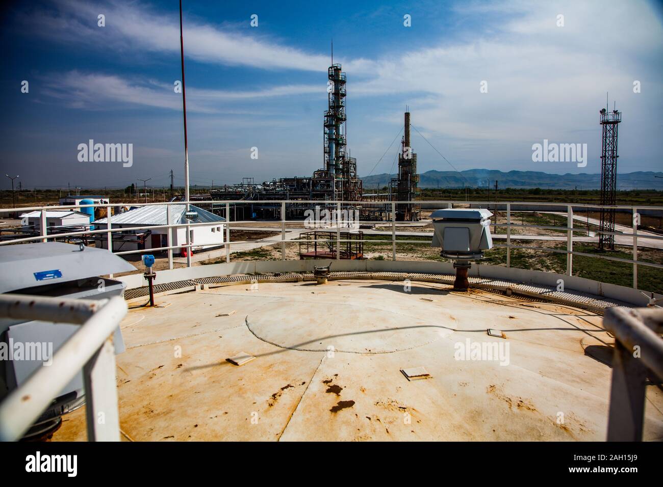 Grau Destillationskolonne auf helle Sonne an einem blauen Himmel mit Wolken auf Ölraffinerie Werk in eine Wüste. Stockfoto