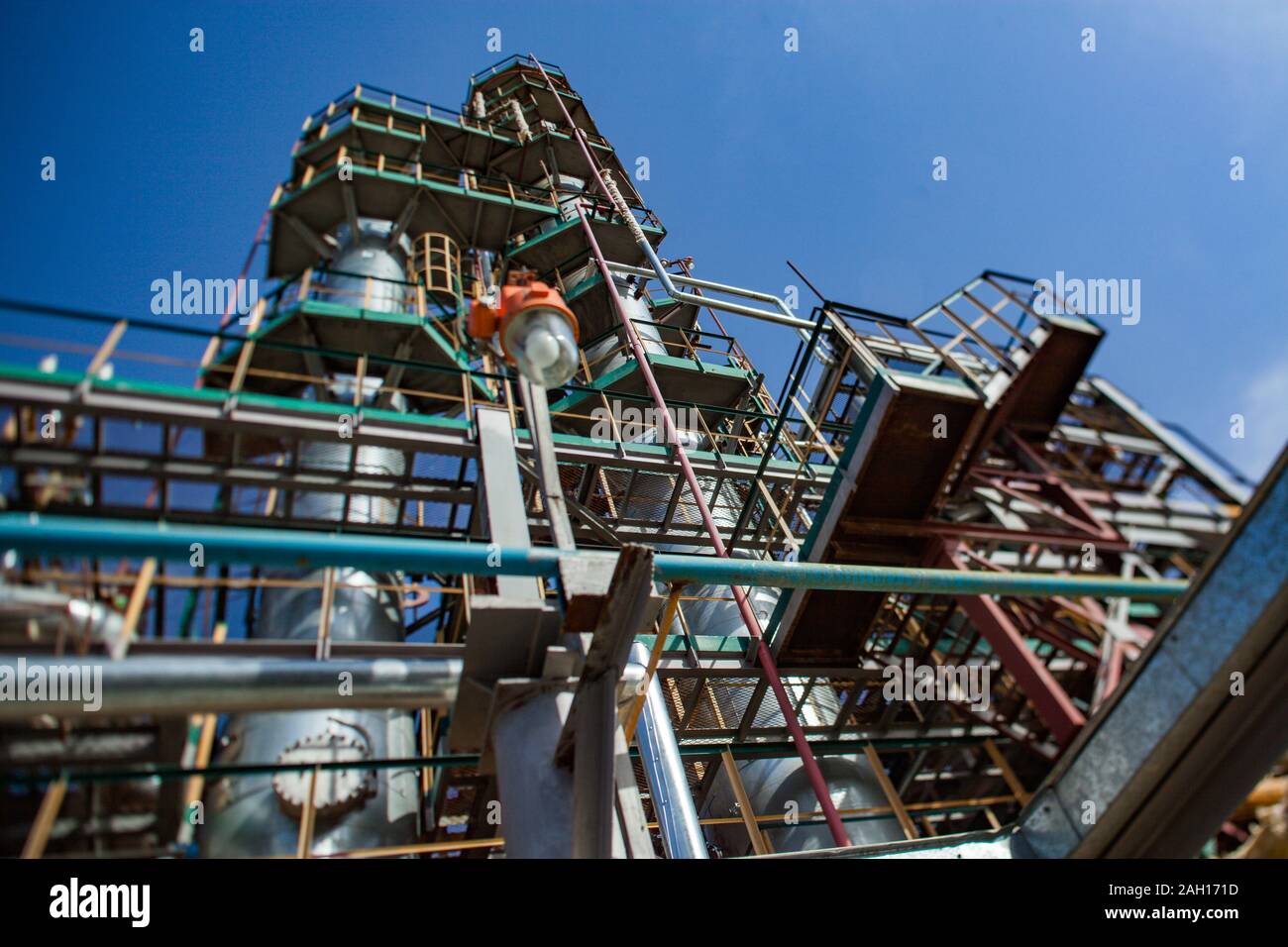 Grau die Raffination von Spalten und Pipelines in der Öl verarbeitenden Betrieb auf einem blauen Himmel. Stockfoto