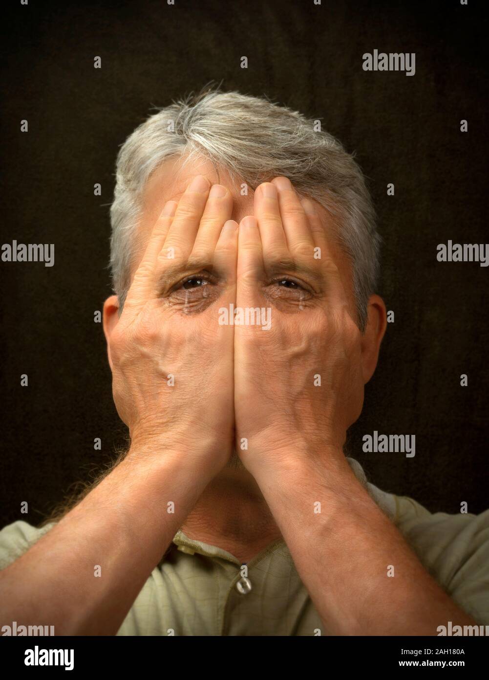 Weinenden Mann versucht, sein Gesicht mit den Händen zu verbergen und seine Gefühle nicht zeigen, aber seine gefüllt riss die Augen zeigen durch Aufdeckung seiner Traurigkeit, depr Stockfoto