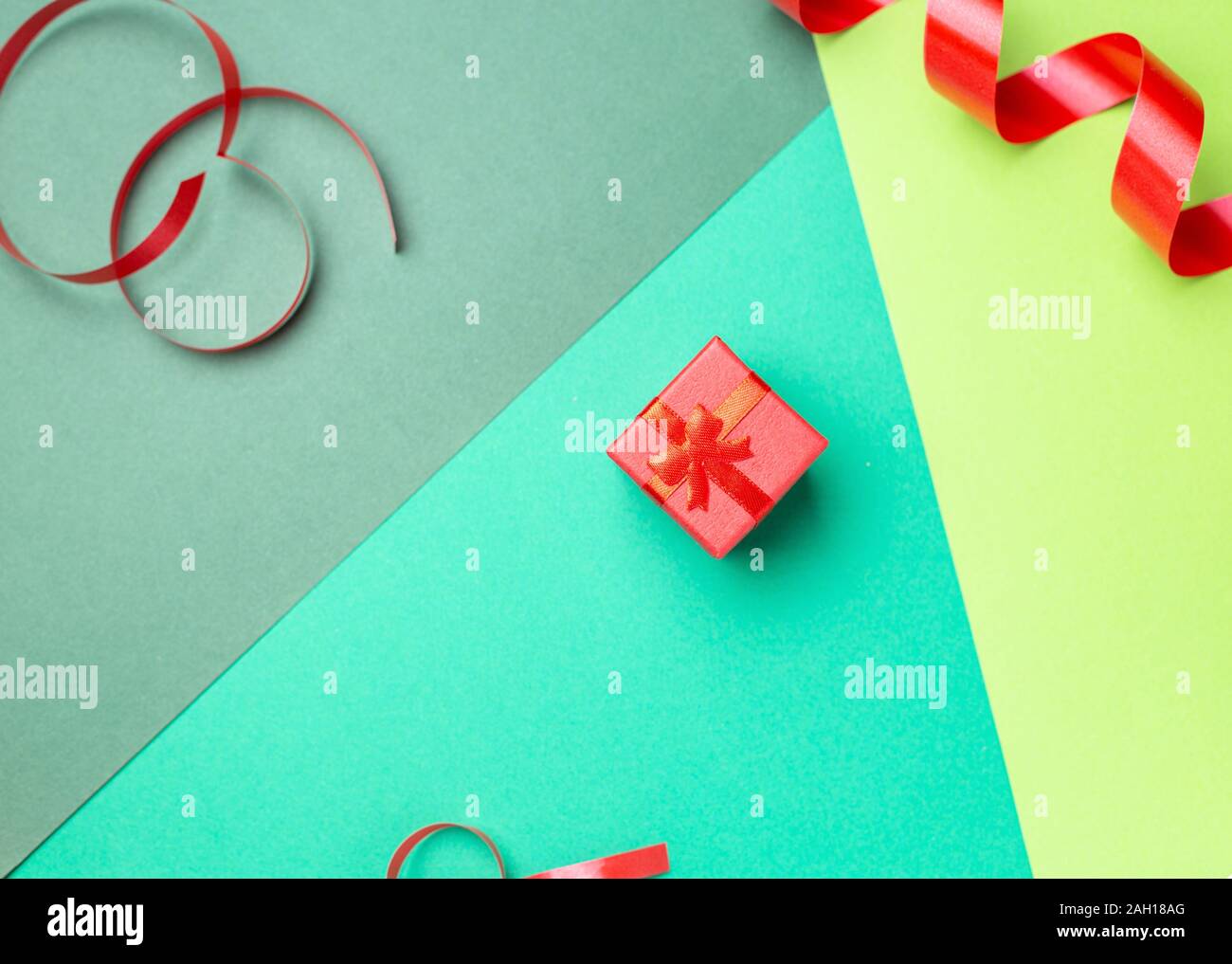 Minimalistische Grußkarte mit roter Geschenkbox über Pastellfarben Hintergrund Stockfoto