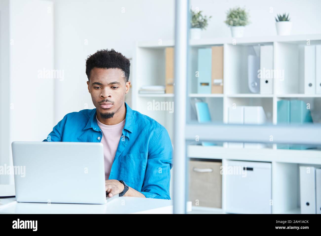 Schweren afrikanischen Büroangestellter in Freizeitkleidung online Arbeiten am Laptop sitzen an seinem Arbeitsplatz im Büro Stockfoto