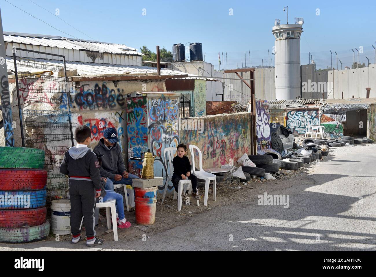 Bethlehem, West Bank. 23 Dez, 2019. Palästinenser in der Nähe eines israelischen Wachturm in der Trennwand in der biblischen Stadt Bethlehem, West Bank, am Montag, 23. Dezember 2019. Eine neue Art der Arbeit mit der Überschrift "Auto von Bethlehem" durch Graffiti Künstler Banksy, zeigt eine Krippe vor dem israelischen Trennungsmauer, ist an seinem Walled-Off Hotels in der Nähe angezeigt. Foto von Debbie Hill/UPI Quelle: UPI/Alamy leben Nachrichten Stockfoto